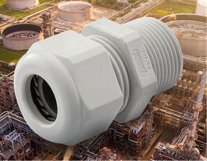 Large industrial piping coupling or union connector on an oil/refinery site, gray and threaded with factory background