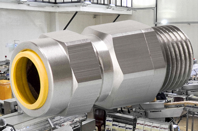 Large metallic pipe coupling with a yellow inner gasket in an industrial workshop setting